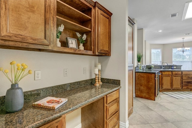 kitchen with dark stone counters, decorative light fixtures, a chandelier, sink, and light tile floors