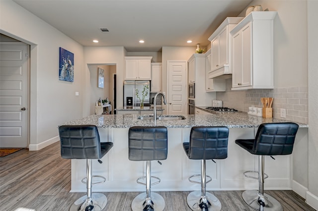 kitchen featuring tasteful backsplash, light hardwood / wood-style floors, stainless steel appliances, and sink