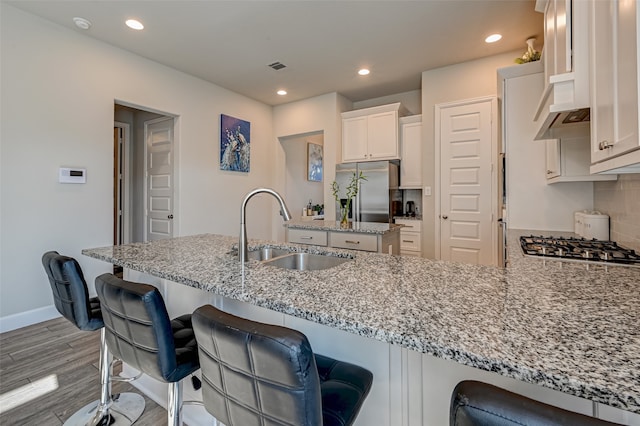 kitchen featuring appliances with stainless steel finishes, light stone counters, light hardwood / wood-style floors, and sink