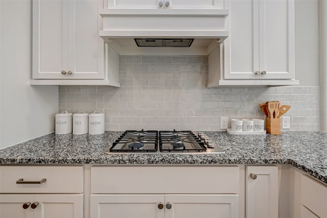 kitchen with dark stone counters, white cabinetry, stainless steel gas cooktop, and tasteful backsplash