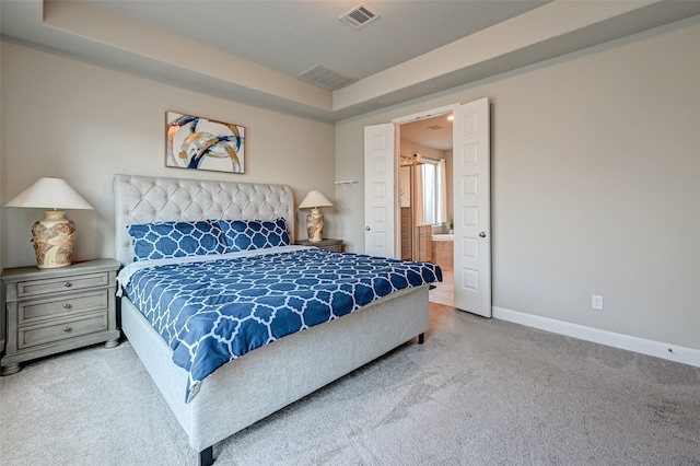 bedroom with ensuite bathroom and light carpet