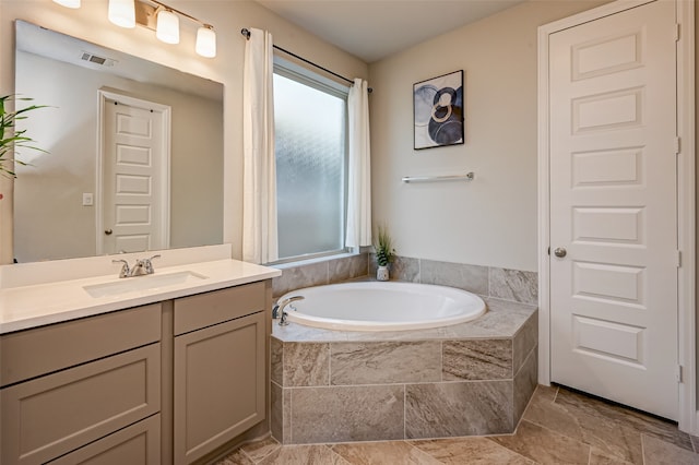 bathroom featuring tile flooring, a relaxing tiled bath, and vanity