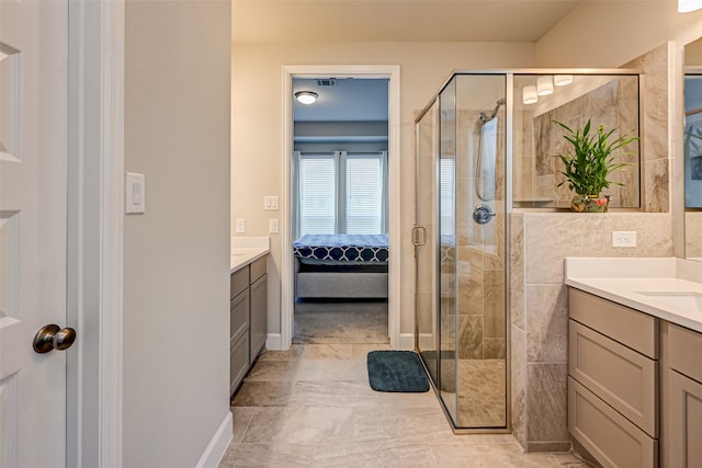 bathroom with a shower with door, tile floors, and vanity