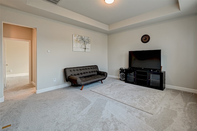 sitting room with a raised ceiling and light colored carpet