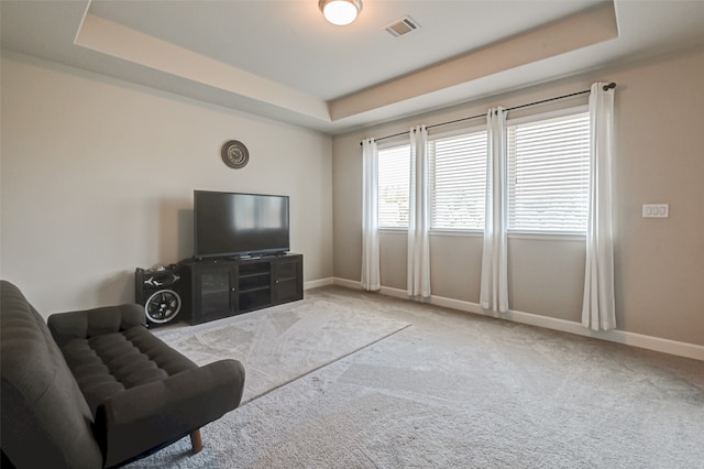 living room featuring light colored carpet and a tray ceiling