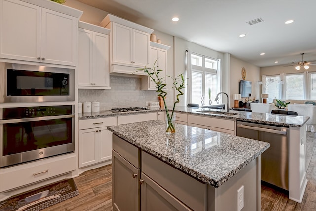 kitchen with a kitchen island, ceiling fan, appliances with stainless steel finishes, and a wealth of natural light