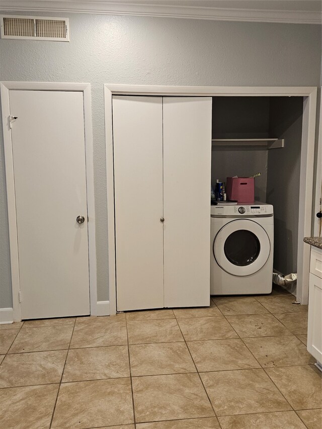 laundry area featuring washer / clothes dryer, light tile floors, and ornamental molding