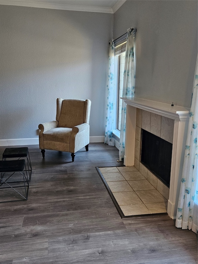 living area with crown molding, wood-type flooring, and a tile fireplace