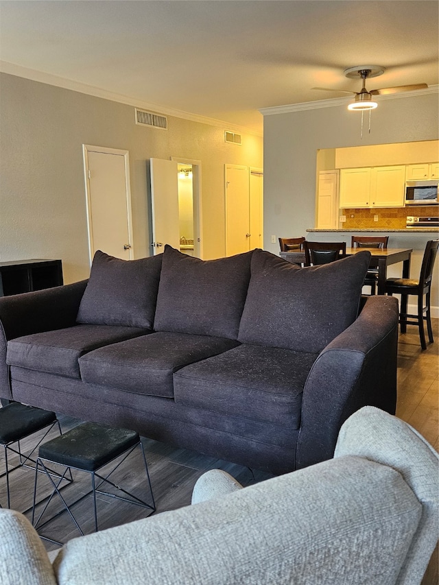 living room featuring ceiling fan, dark wood-type flooring, and crown molding