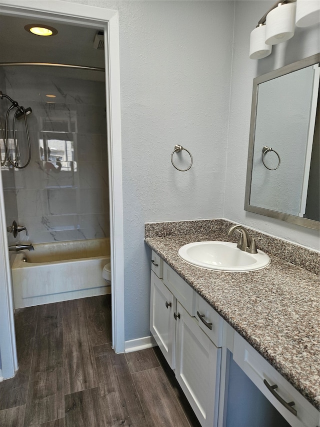 full bathroom featuring hardwood / wood-style flooring, tiled shower / bath combo, toilet, and vanity