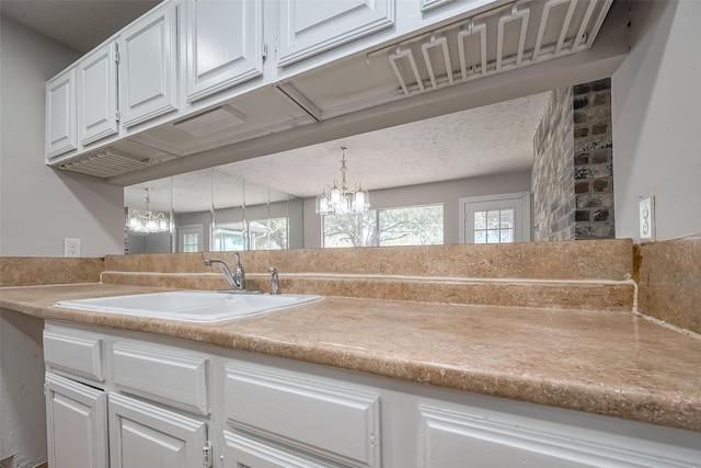 7635 Loro Linda Dr, Houston, TX 77083 - kitchen with a sink, an inviting chandelier, light countertops, and white cabinetry
