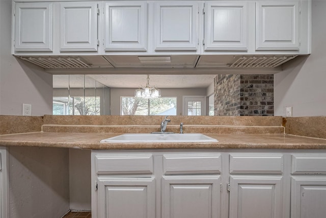 7635 Loro Linda Dr, Houston, TX 77083 - kitchen featuring a sink, an inviting chandelier, light countertops, and white cabinetry