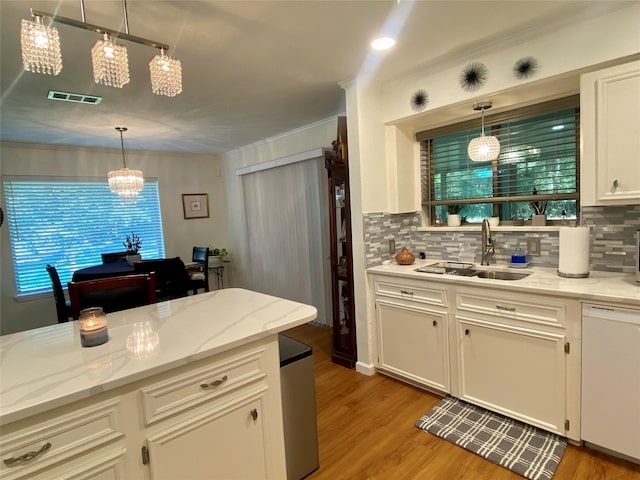 kitchen with white cabinetry, dishwasher, sink, hanging light fixtures, and backsplash