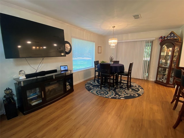 dining room with hardwood / wood-style floors, an inviting chandelier, a healthy amount of sunlight, and crown molding