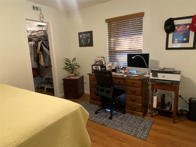 bedroom with a walk in closet, a closet, and hardwood / wood-style floors