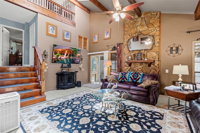 tiled living room with plenty of natural light, beam ceiling, ceiling fan, and a wood stove