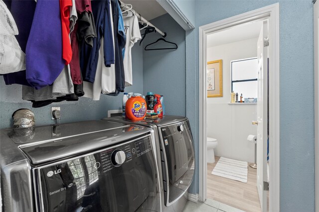 clothes washing area with washer and dryer, electric dryer hookup, hookup for a washing machine, and light hardwood / wood-style flooring