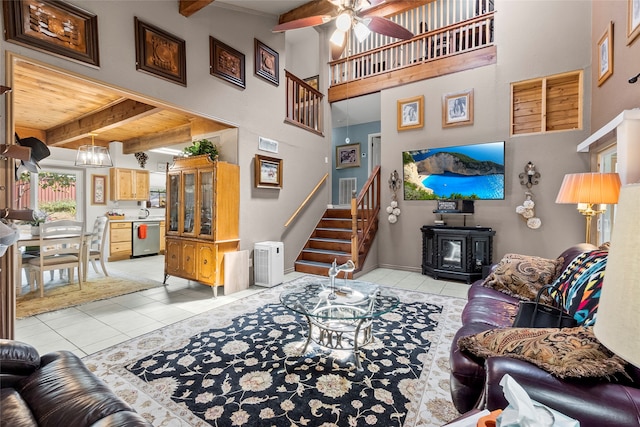 tiled living room with beam ceiling, wood ceiling, ceiling fan with notable chandelier, and a wood stove