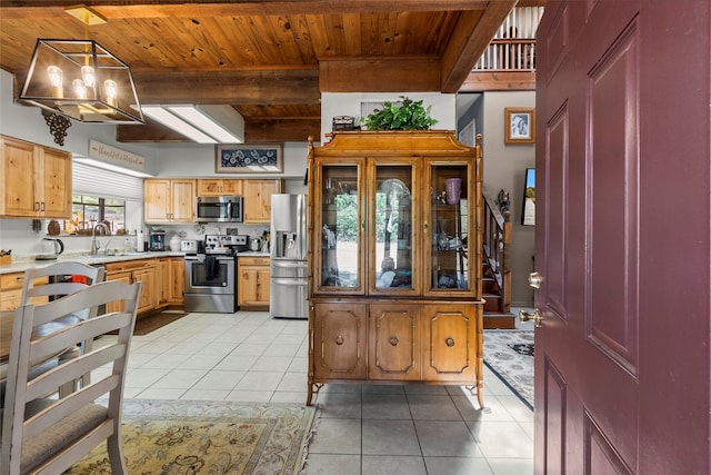 kitchen with appliances with stainless steel finishes, light tile floors, beamed ceiling, and pendant lighting