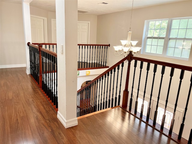 stairway with a chandelier and dark hardwood / wood-style flooring