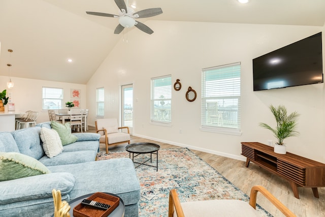 living room with ceiling fan, light wood-type flooring, and high vaulted ceiling