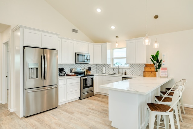 kitchen with kitchen peninsula, hanging light fixtures, backsplash, stainless steel appliances, and white cabinets