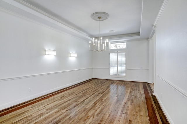 unfurnished room with a tray ceiling, crown molding, hardwood / wood-style floors, and a chandelier