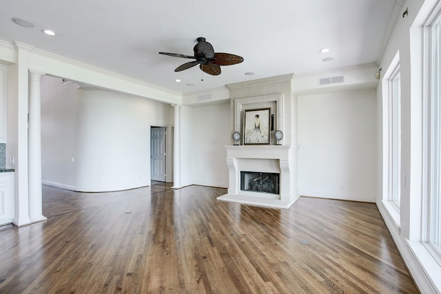 unfurnished living room with a large fireplace, dark hardwood / wood-style floors, ceiling fan, and ornamental molding