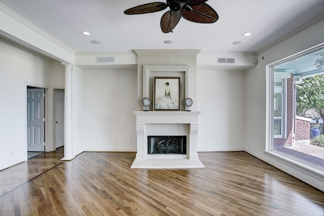 unfurnished living room featuring a textured ceiling, ceiling fan, crown molding, a fireplace, and hardwood / wood-style floors