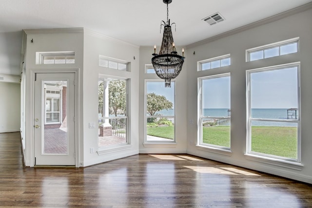 entryway with dark hardwood / wood-style flooring, a water view, ornamental molding, and a notable chandelier