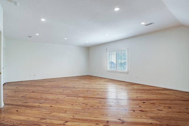 unfurnished room featuring light hardwood / wood-style floors and vaulted ceiling