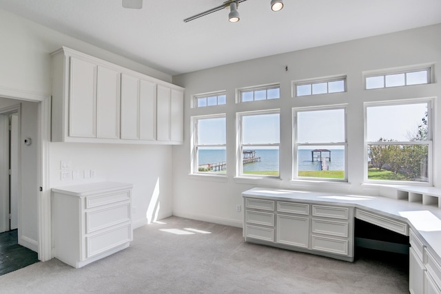 carpeted office space with built in desk, a water view, and a wealth of natural light