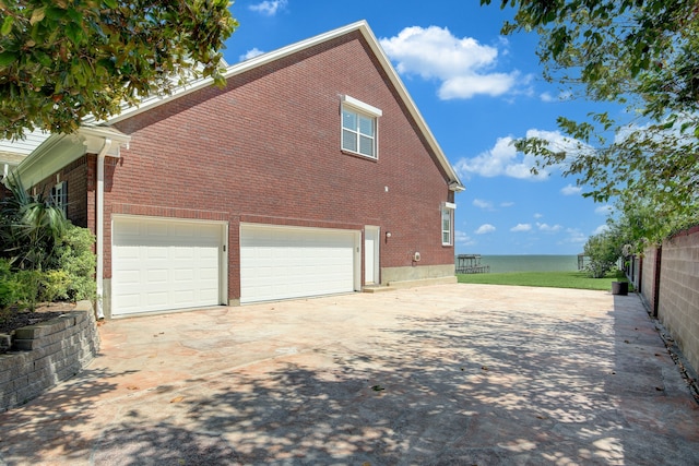 view of home's exterior with a water view and a garage