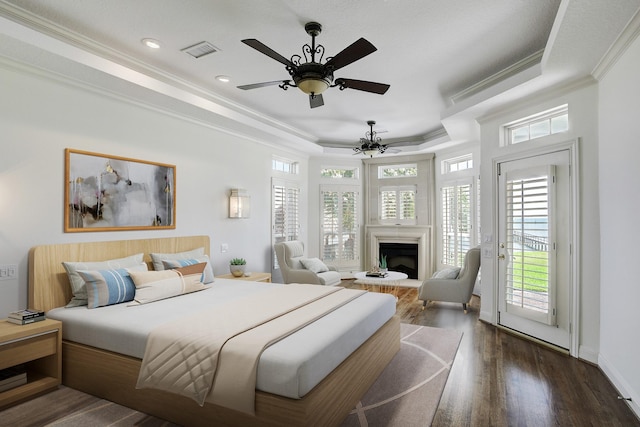 bedroom featuring access to exterior, dark hardwood / wood-style flooring, a raised ceiling, and ceiling fan