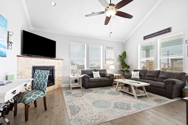 living room featuring a tile fireplace, high vaulted ceiling, ceiling fan, ornamental molding, and hardwood / wood-style floors