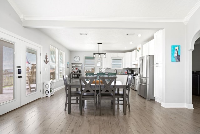 dining room with dark wood-type flooring, an inviting chandelier, a textured ceiling, french doors, and ornamental molding