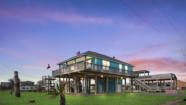 back house at dusk featuring a balcony and a lawn