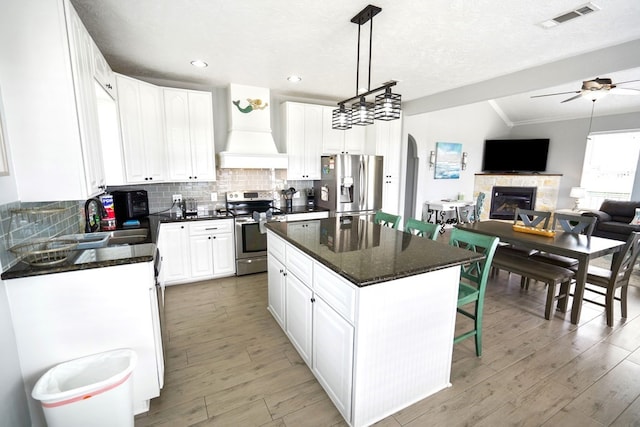 kitchen with custom range hood, a kitchen island, stainless steel appliances, and white cabinetry