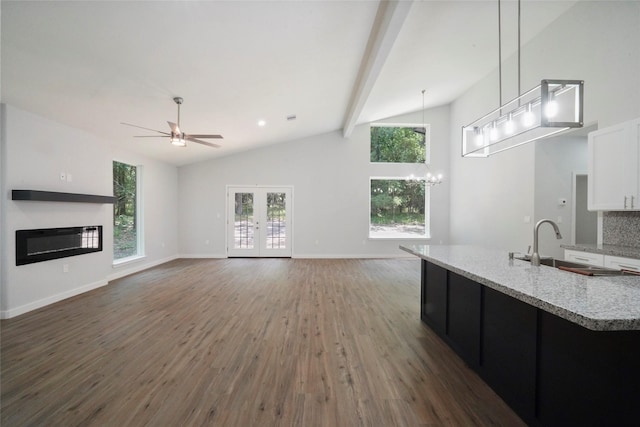 unfurnished living room featuring beam ceiling, plenty of natural light, wood finished floors, and a sink