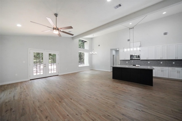 kitchen with tasteful backsplash, stainless steel microwave, visible vents, open floor plan, and white cabinets