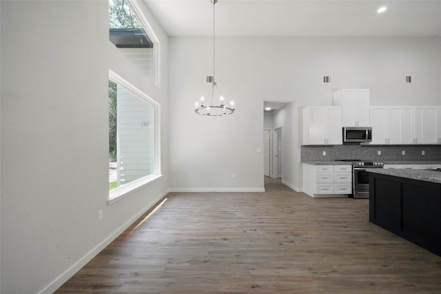 kitchen featuring a notable chandelier, tasteful backsplash, wood finished floors, appliances with stainless steel finishes, and white cabinets