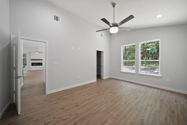 interior space featuring baseboards, wood finished floors, visible vents, and high vaulted ceiling