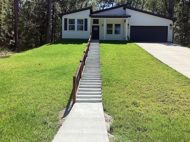 mid-century modern home featuring driveway, a front yard, and an attached garage