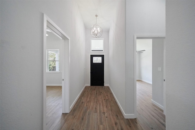 entrance foyer featuring a chandelier, dark wood-type flooring, and baseboards