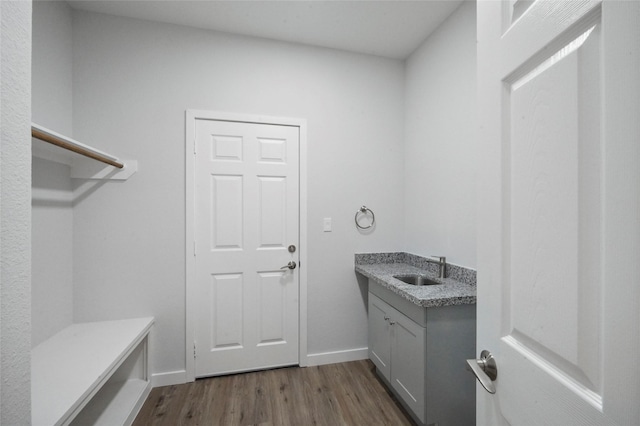 laundry room with a sink, baseboards, and dark wood-type flooring