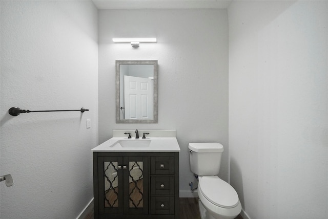 bathroom featuring toilet, vanity, and baseboards