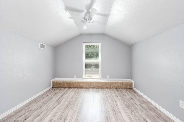 additional living space featuring ceiling fan, a textured ceiling, light hardwood / wood-style flooring, and vaulted ceiling