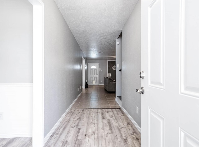 corridor featuring a textured ceiling and light wood-type flooring