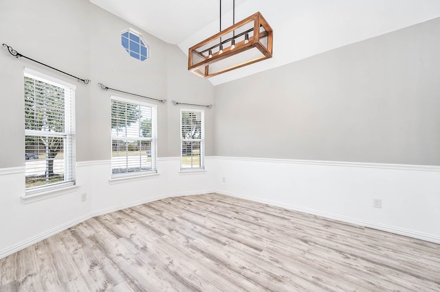 spare room featuring vaulted ceiling, a wealth of natural light, and light hardwood / wood-style flooring