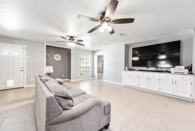 living room featuring ceiling fan and a textured ceiling